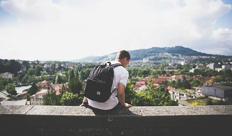 Person sitting on a ledge, overlooking a city