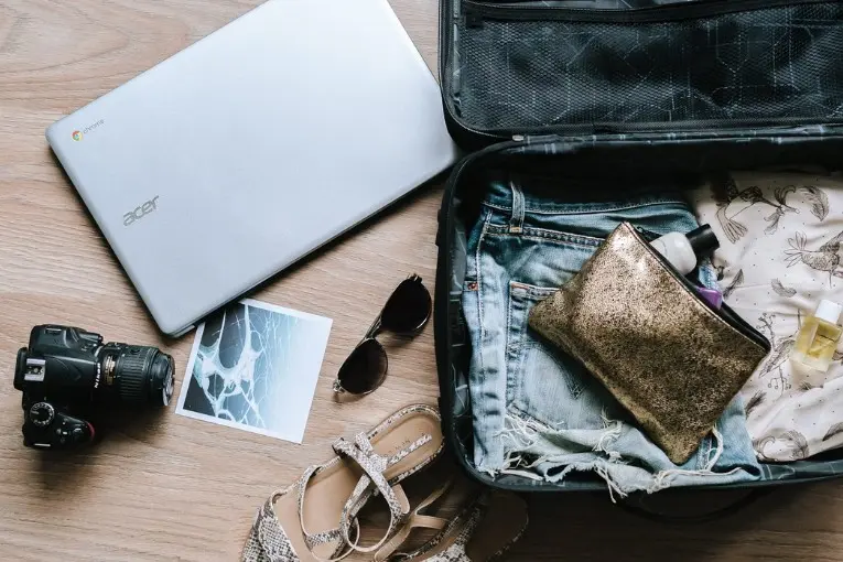laptop and clothes near travel luggage