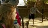 Lady with a backpack, smiling while holding on railing at a zoo