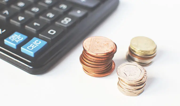 Corner of calculator with stacks of coins